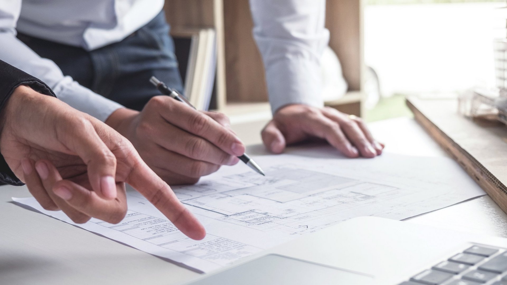 Engineering or Creative architect in construction project, Engineers hands working on construction blueprint and building model at a workplace in office, Building and architecture concept